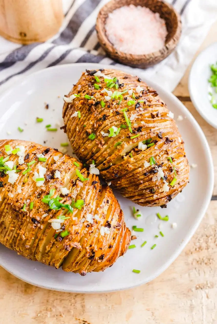 Air fryer hasselback potatoes on a plate with garlic butter and fresh chives