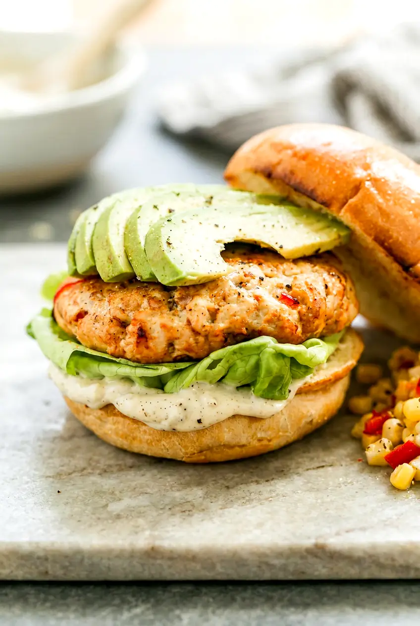 Air fryer chicken burgers on brioche buns with avocado, lettuce, and garlicky aioli