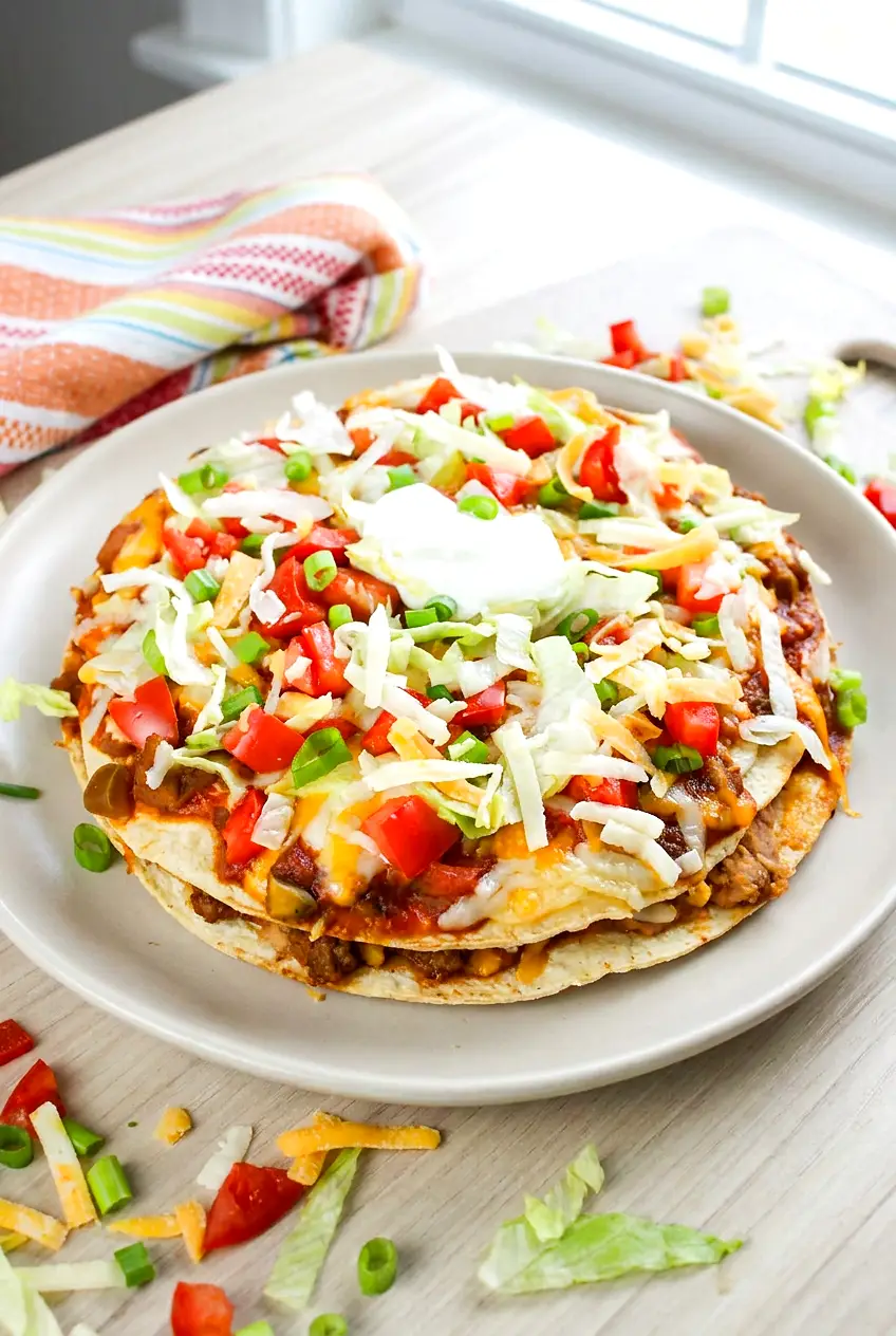 Air Fryer Mexican pizza served on a plate with crisp tortillas, melted cheese, beef, and fresh toppings