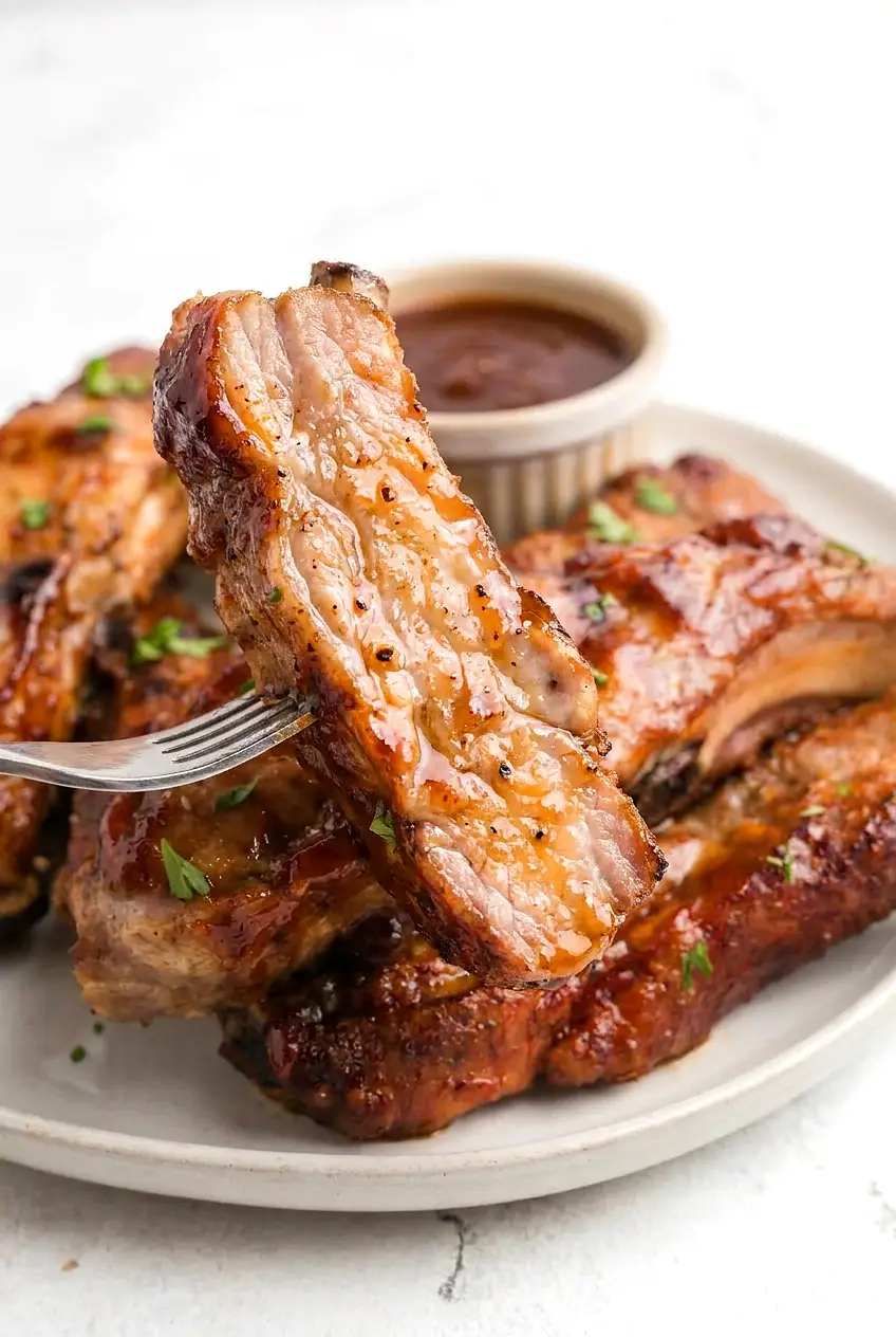 Close-up of air fryer country-style rib sliced to show juicy interior, smoky paprika rub, and tacky BBQ glaze with browned edges.