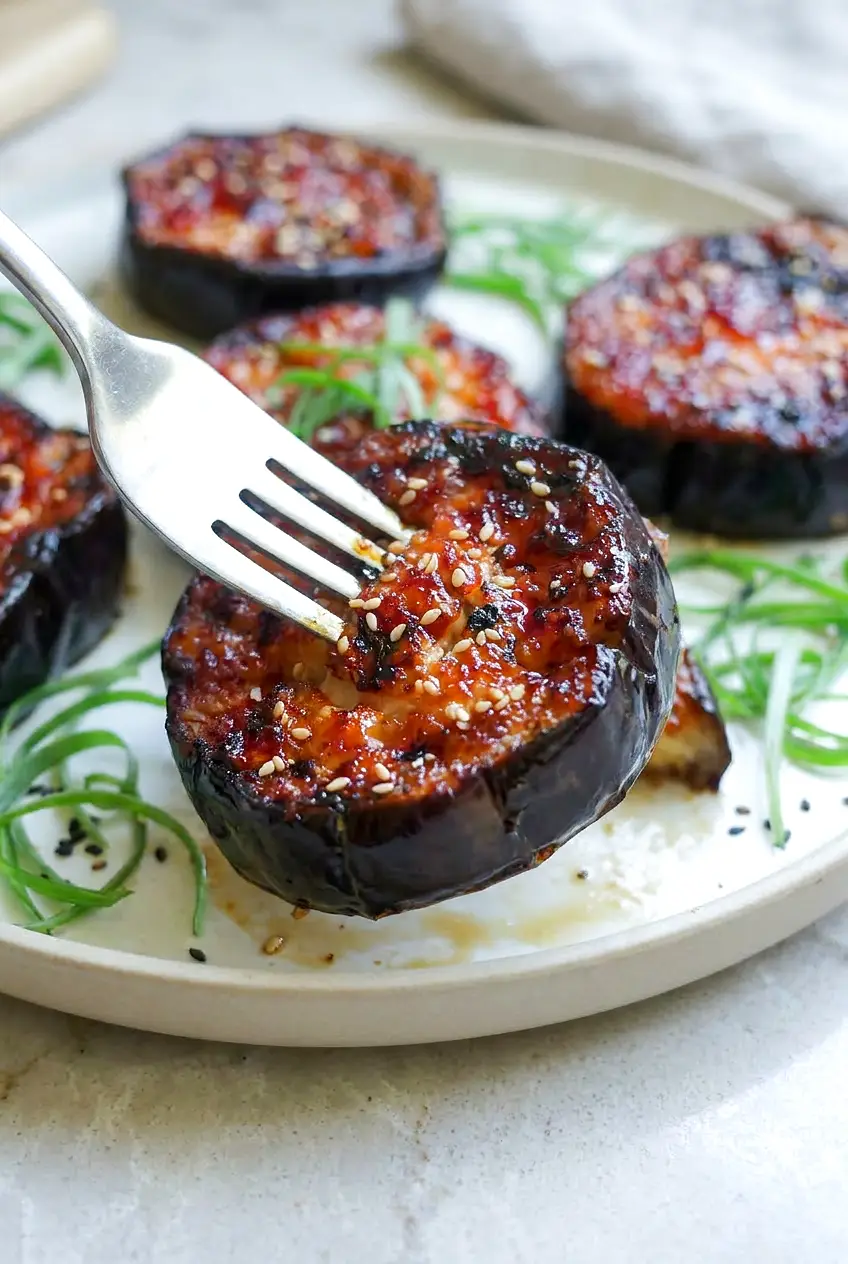 Close-up of air fryer miso glazed eggplant showing creamy interior, glossy glaze, sesame seeds, and scallions.