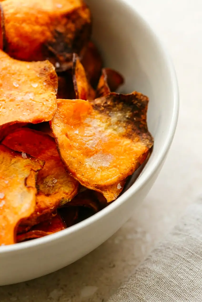 Close-up of thin Air Fryer sweet potato chips with curled, crisp edges and light salt crystals.