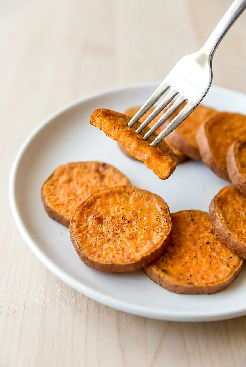 Close-up of air fryer sweet potato slice showing tender center and lightly browned, crisp edge with cinnamon specks.