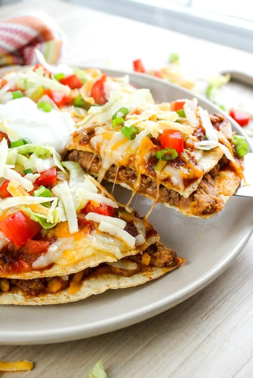 Close-up of Air Fryer Mexican pizza showing the melted cheese, seasoned beef, and crisp tortilla layers
