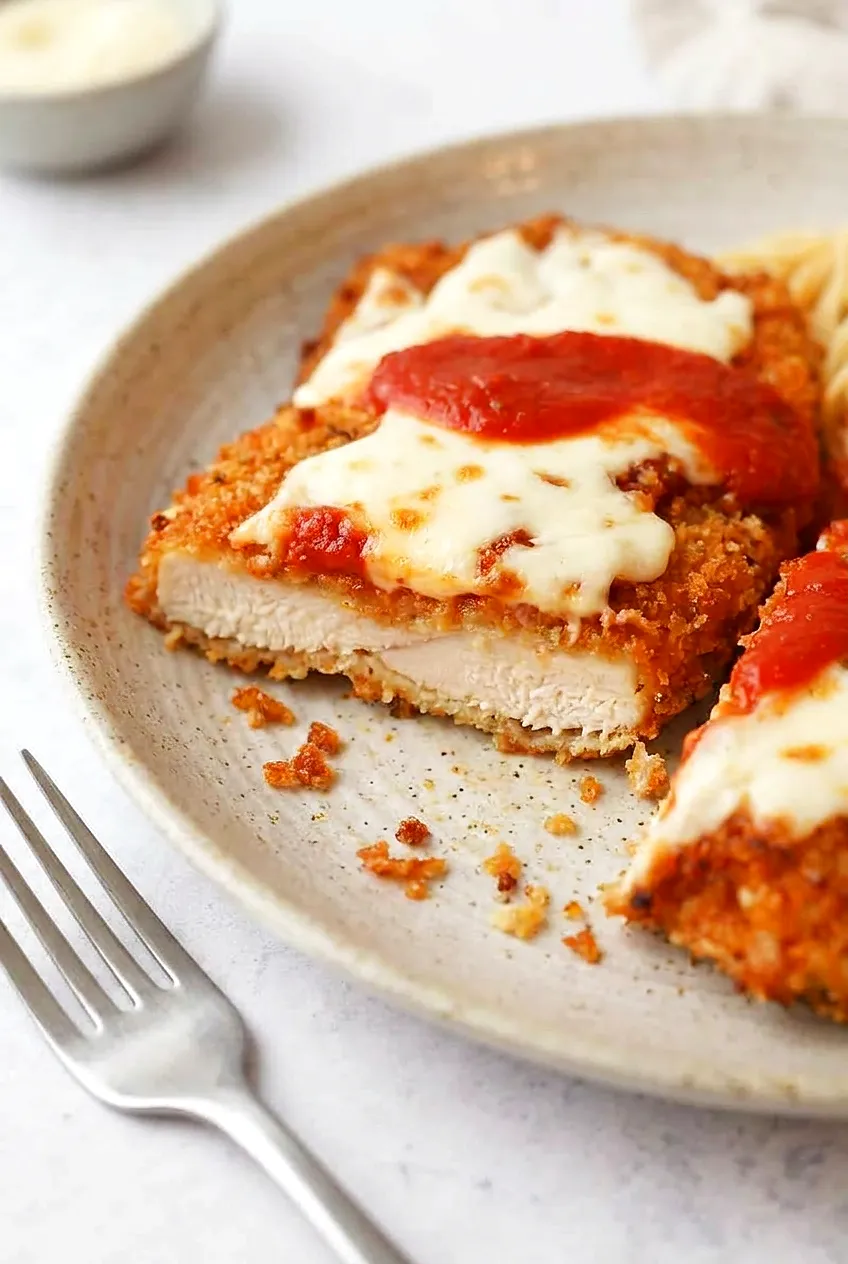 Close-up sliced Air Fryer Chicken Parmesan with juicy white meat, crisp golden panko crust, and melted cheese with marinara.