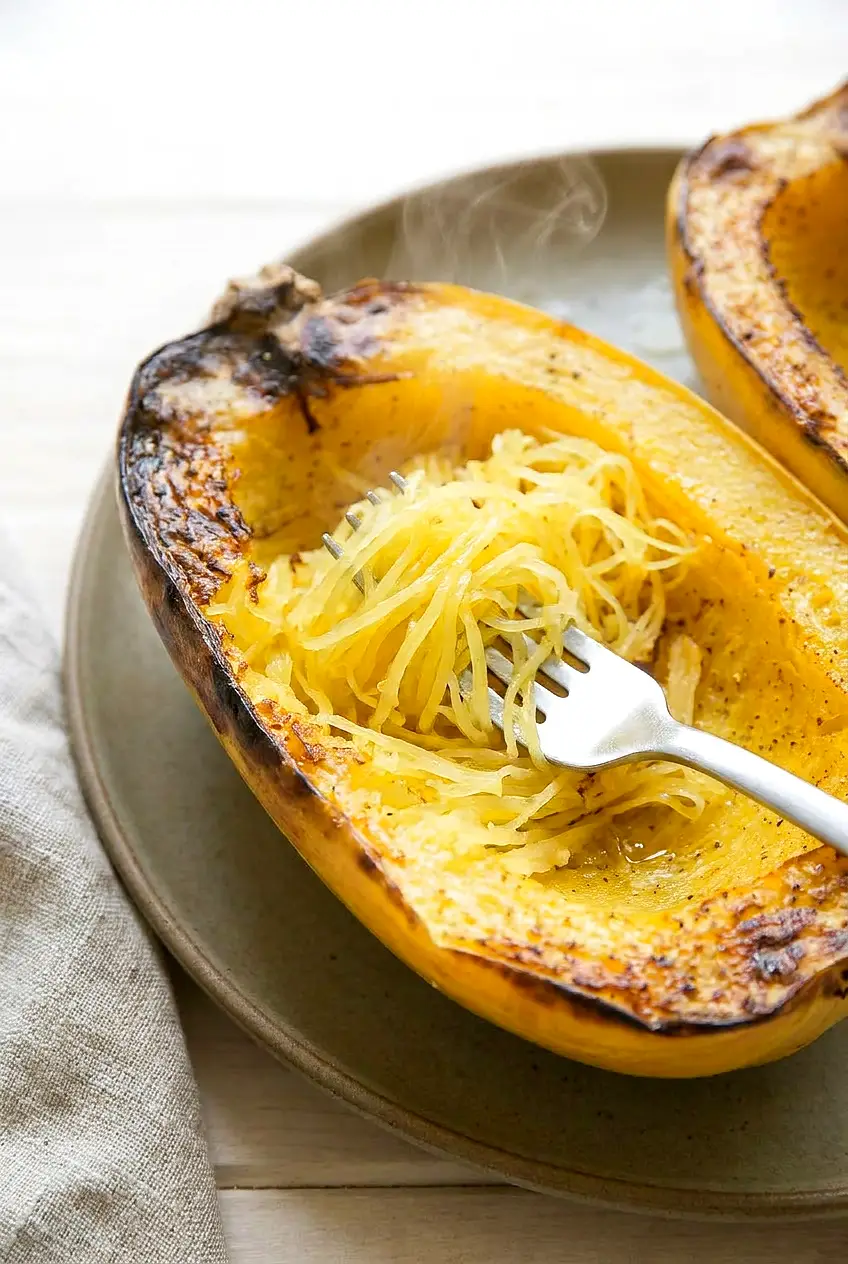 Close-up of Air Fryer spaghetti squash strands scraped with a fork, showing tender, separate strands and browned edges.