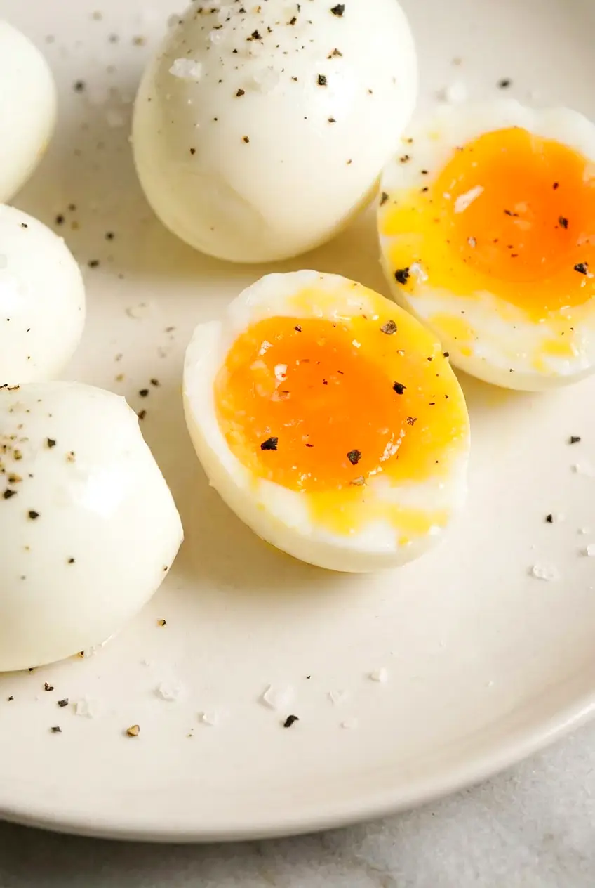 Close-up of a soft-boiled egg cut open with a runny yolk and salt and pepper