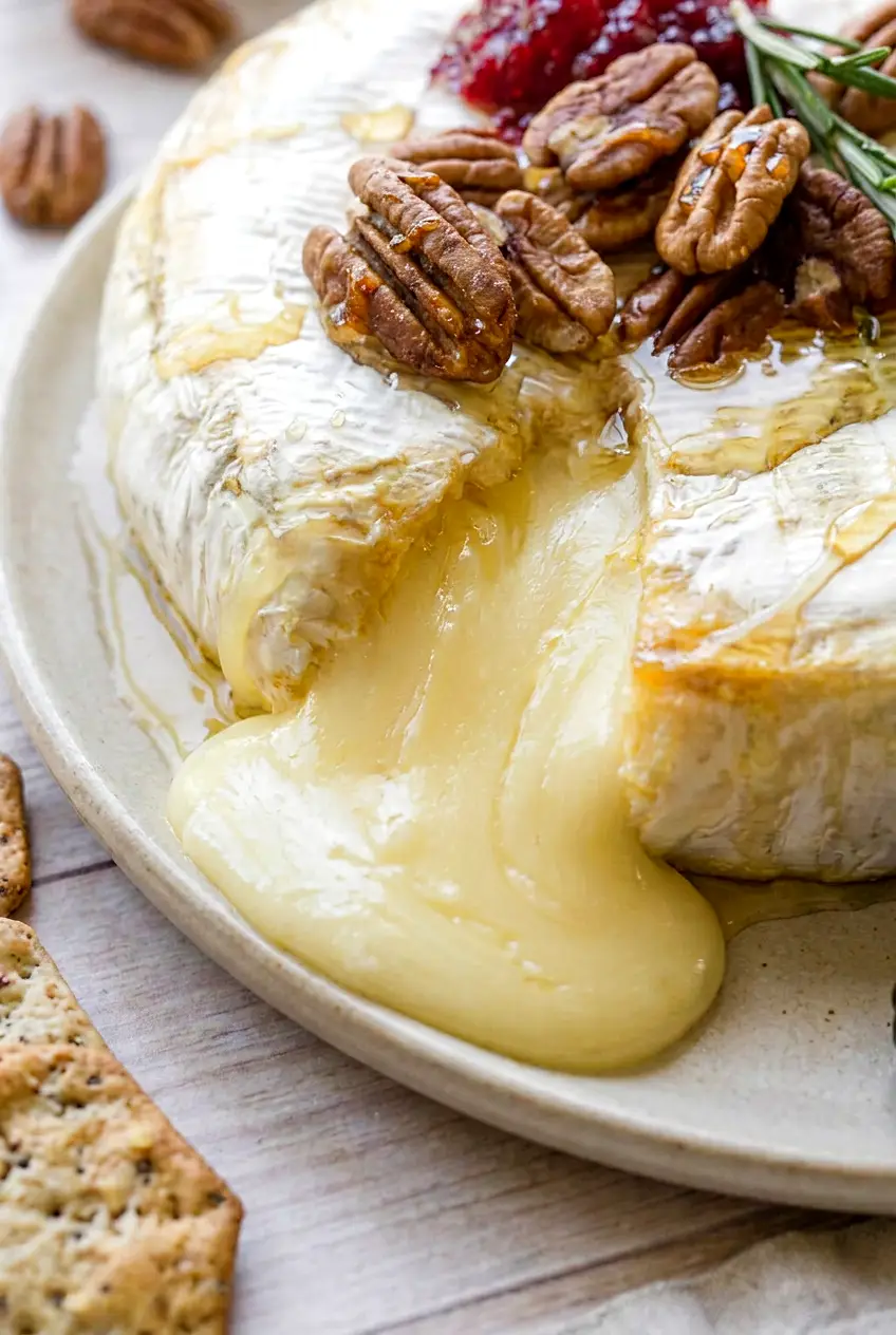 Close-up of air fryer brie with a gooey melted center, lightly puffed rind, and honey drizzle
