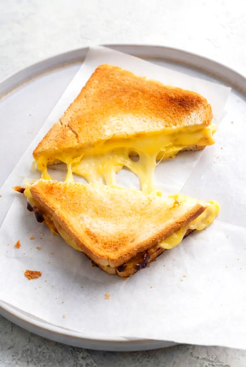 Air fryer grilled cheese sandwich sliced in half on a plate with parchment paper