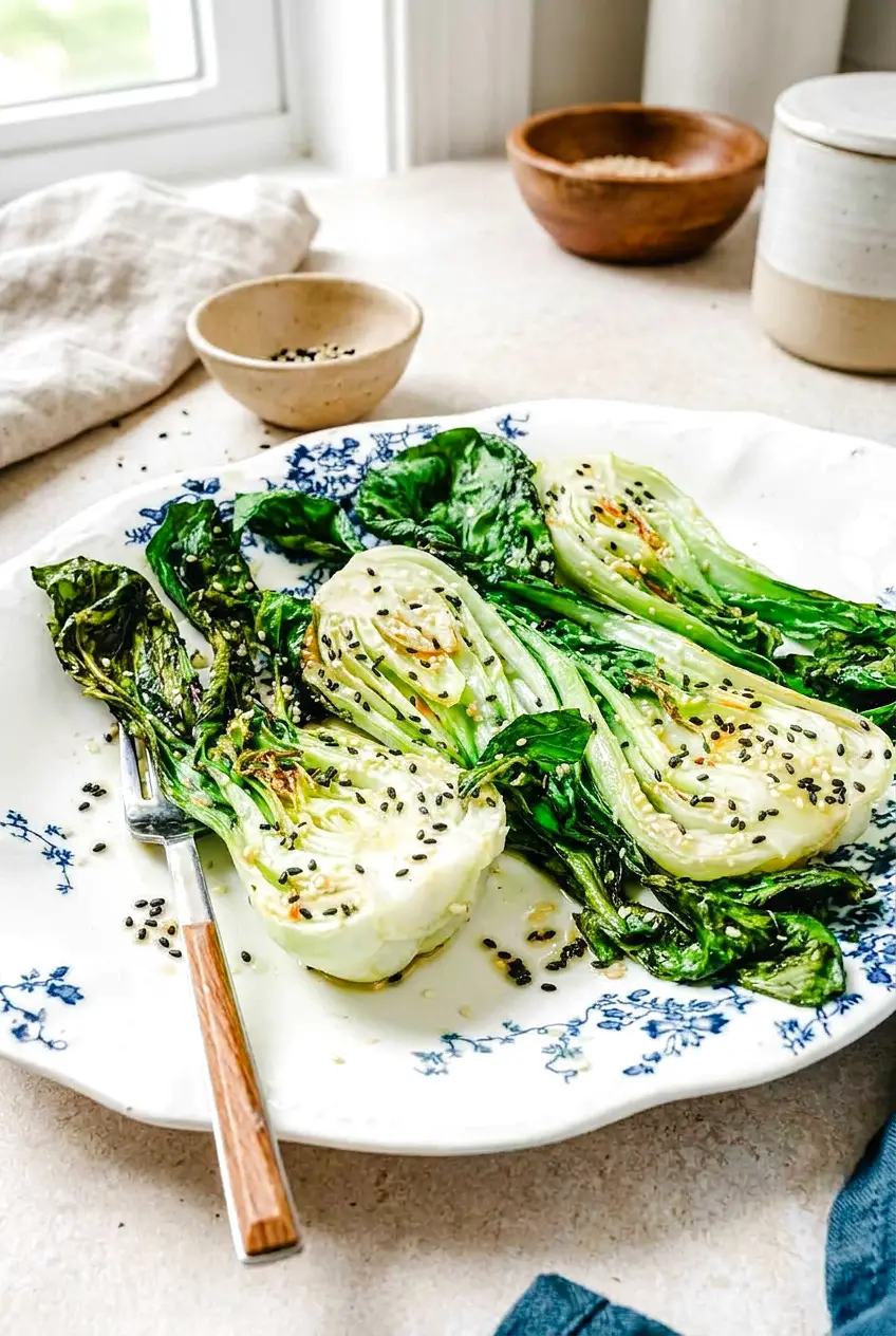 Air fryer bok choy served on a blue and white plate with lightly browned edges and sesame seeds