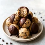 Air fryer cookie dough bites served on a plate with chocolate chips and a glossy chocolate coating