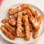 Cinnamon sugar air fryer apple fries with golden panko coating on a white plate.