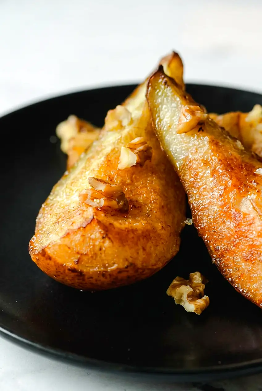 Close-up of air fryer pears with cinnamon showing tender centers, caramelized edges, and walnut topping.